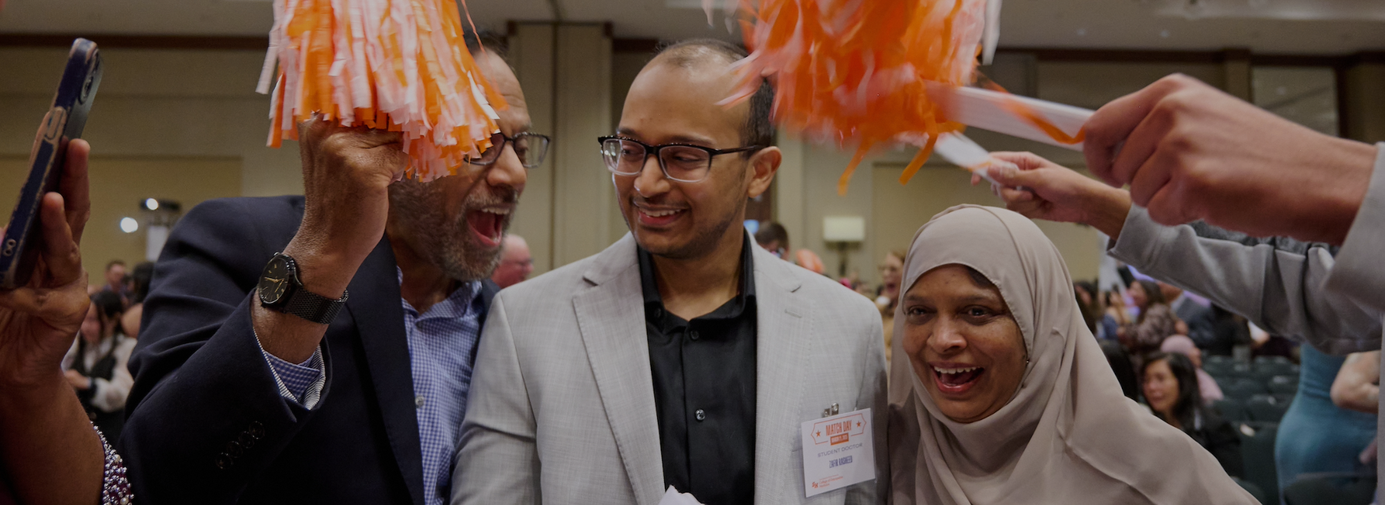student surrounded by family with pompoms celebrating match day